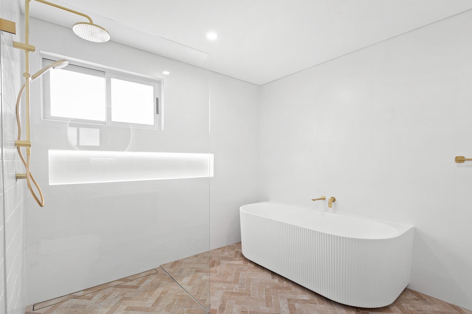Master bathroom with freestanding bath, brass fixtures and herringbone floor — Malabar