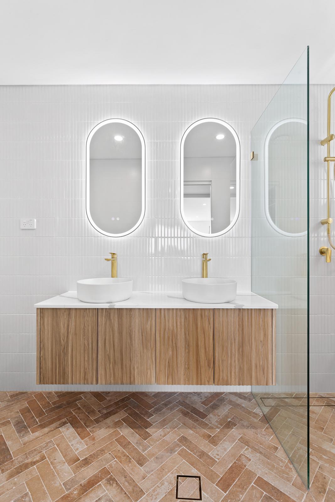 Double vanity ensuite with pill mirrors and brass tapware — Malabar